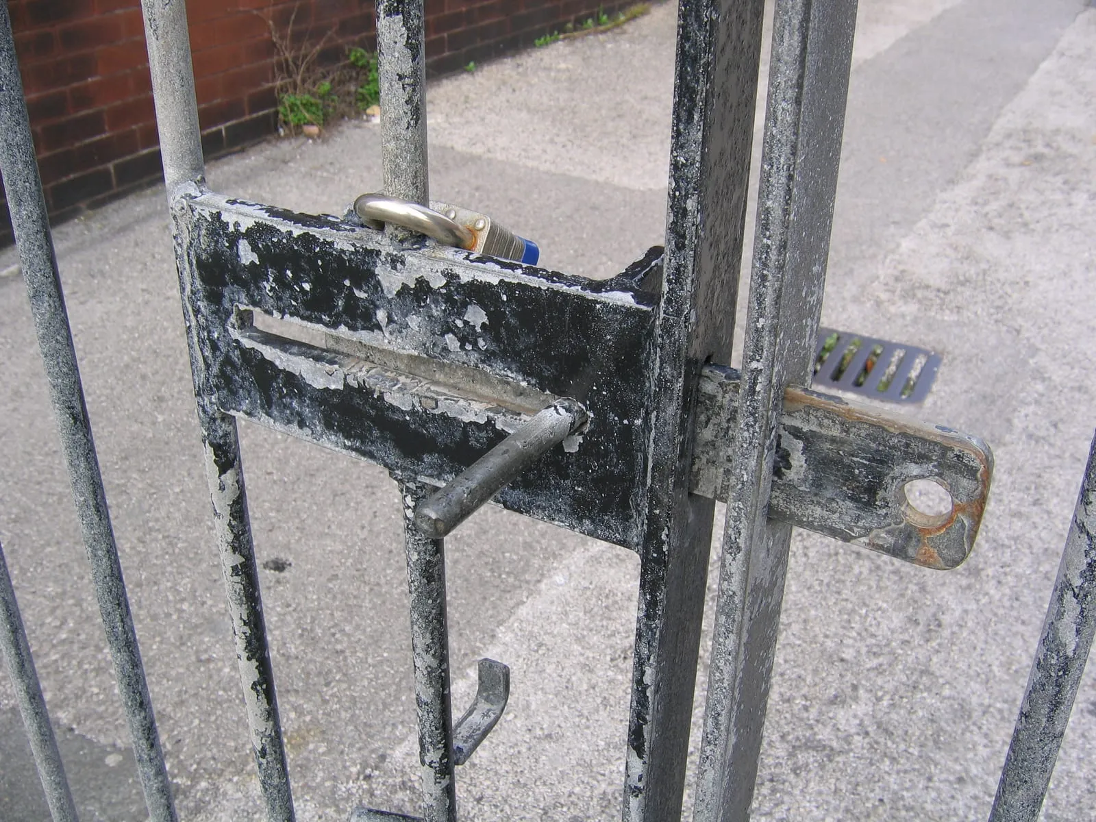 Iron gate closed with a latch and a padlock