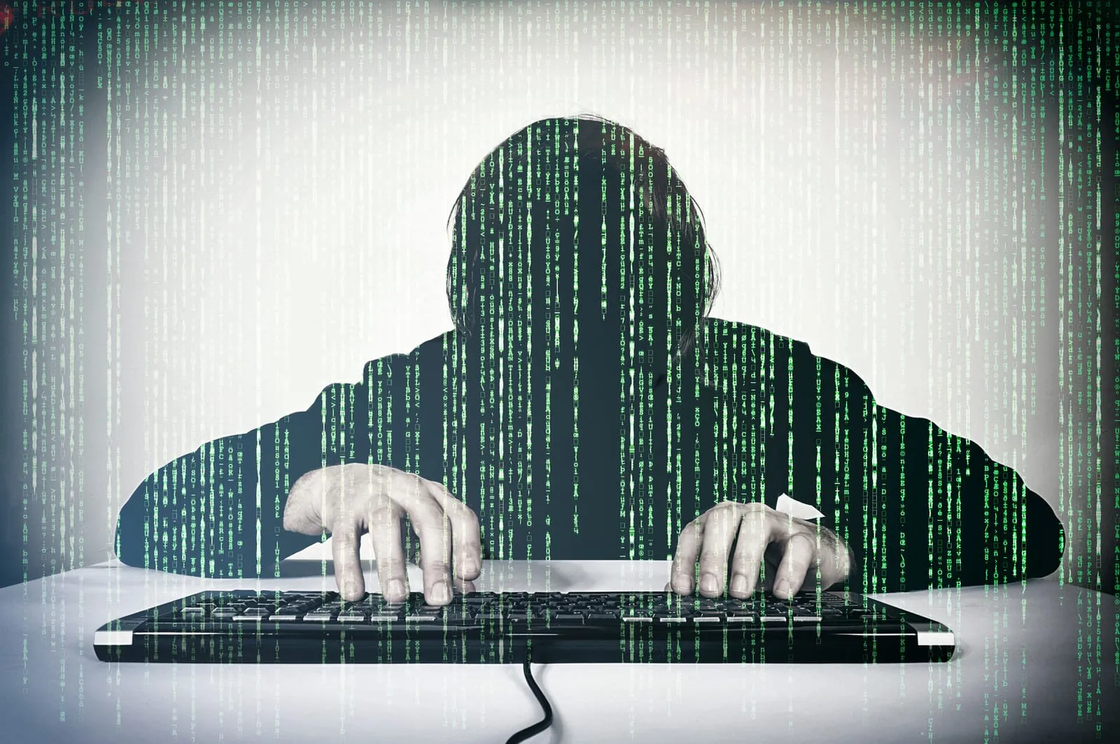 Faceless figure at a keyboard, overlaid with columns of green characters