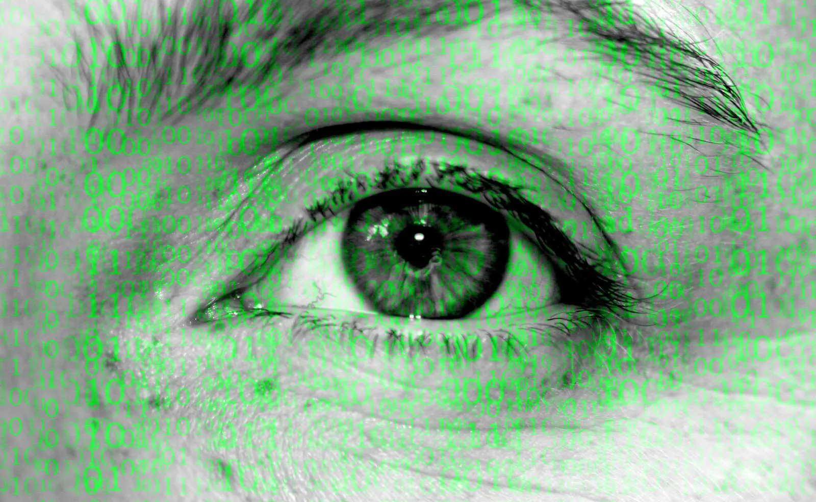 Close-up of an eye with lines of green code overlaid